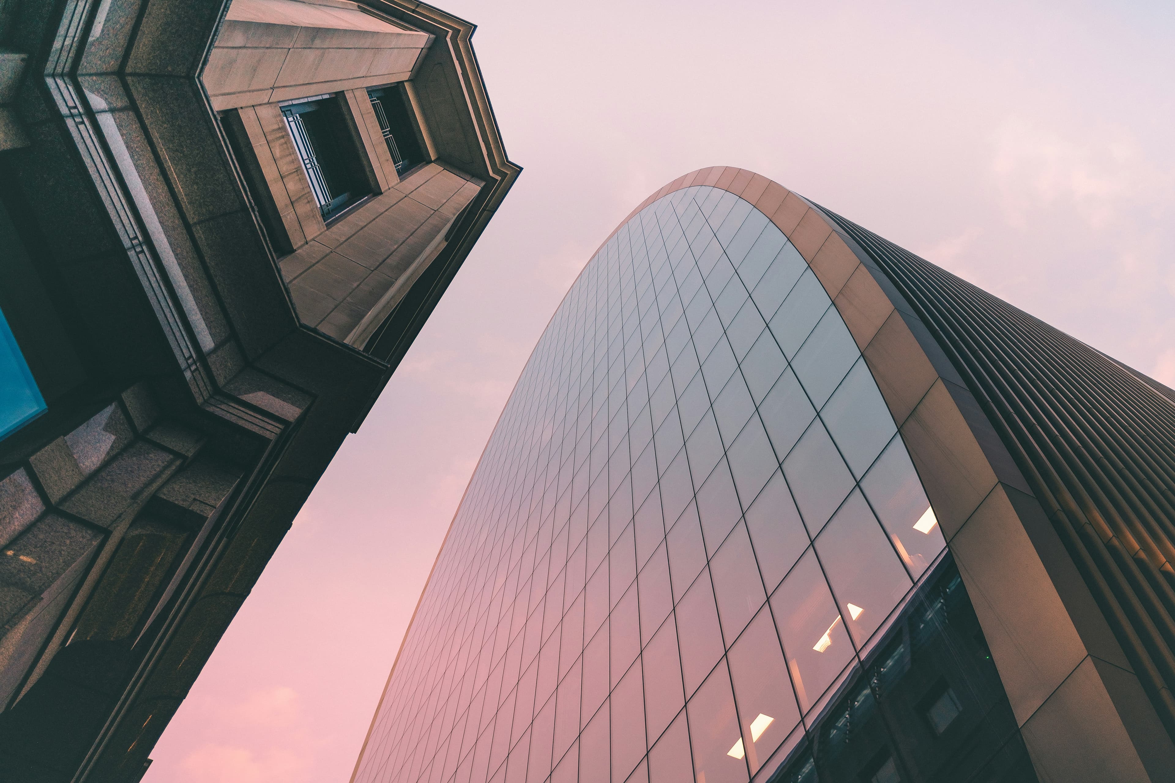 Curved modern glass tower against a soft evening sky